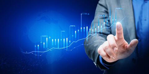 Wall Mural - Close up of businessman hand pointing at abstract glowing growing global business chart on blurry blue background. Financial growth and trade concept.