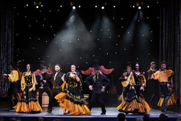 A collective of musicians, singers and dancers in gypsy costumes perform on stage.