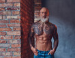Muscular elderly man with tattooed body indoors room