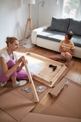 Wall Mural - Mother and daughter assembling new furniture - moving in into a new home.