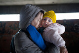 Fototapeta Lawenda - Loving mother holding her child in the bomb shelter