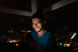 © Lalandrew - Night portrait of smiling man looking in smartphone on background of window.