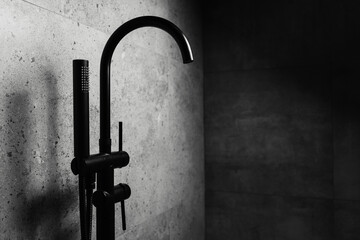 Wall Mural - Photo of black floor-standing bath taps, on the background of dark grey wall.