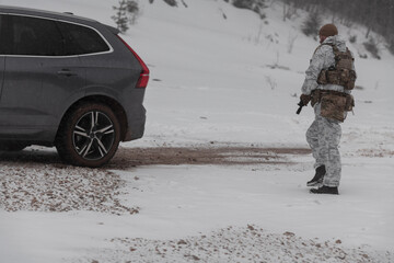 Soldier in winter camouflaged uniform in Modern warfare army on a snow day on forest battlefield with a rifle. Model face very similar to Ukraine prime minister.