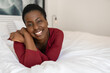 © JonoErasmus - Portrait Black African woman laying on bed, smiling looking into camera