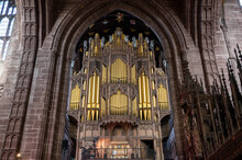 Golden Pipe Organ Beneath A Stone Archway Inside A Cathedral