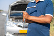 © WESTOCK - car mechanic stading in front of borken on roadside - concept of mobile car service or support, maintenance and assistance.