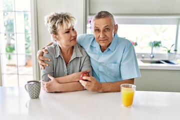 Senior caucasian couple smiling happy having breakfast at the kitchen.