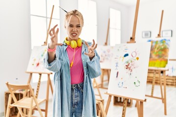 Poster - Young caucasian girl at art studio shouting frustrated with rage, hands trying to strangle, yelling mad