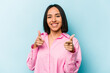 © Asier - Young hispanic woman isolated on blue background cheerful smiles pointing to front.