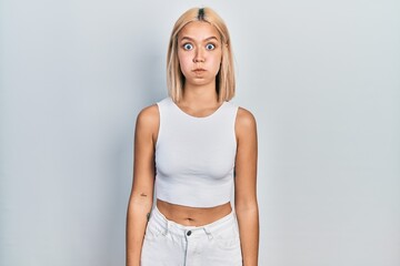 Sticker - Beautiful blonde woman wearing casual style with sleeveless shirt puffing cheeks with funny face. mouth inflated with air, crazy expression.