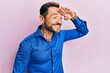 © Krakenimages.com - Middle age man wearing casual clothes very happy and smiling looking far away with hand over head. searching concept.