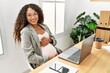 © Krakenimages.com - Young latin woman pregnant smiling confident touching tummy working at office