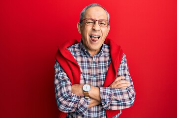 Sticker - Handsome senior man with grey hair wearing casual clothes and glasses sticking tongue out happy with funny expression.