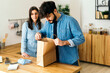© Westend61 - Man looking in paper bag standing by woman in kitchen at home