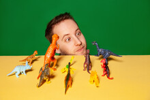 Young Man With Dinosaur Figurines Against Green Background