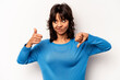 © Asier - Young hispanic woman isolated on white background showing thumbs up and thumbs down, difficult choose concept