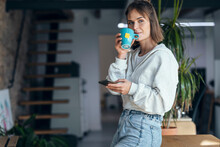 Woman With Mobile Phone Having Tea At Home