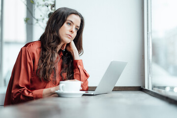 Contemplative woman with laptop in cafe