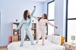 © Krakenimages.com - Woman and girl mother and daughter dancing on bed at bedroom