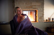 © Westend61 - Woman wrapped in blanket sitting with eyes closed in living room
