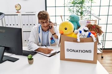 Sticker - Young caucasian man wearing doctor uniform talking on the smartphone at clinic