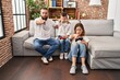 © Krakenimages.com - Family of three playing video game sitting on the sofa pointing with finger to the camera and to you, confident gesture looking serious
