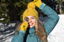 Smiling Woman Wearing Yellow Knit Hat Covering Eye With Navigational Compass On Sunny Day