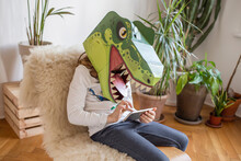 Girl With Dinosaur Mask Using Smart Phone At Home