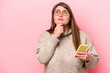 Young caucasian overweight woman holding a mobile phone isolated on pink background looking sideways with doubtful and skeptical expression.