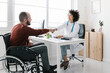 © Westend61 - Disable patient sitting in wheelchair shaking hand with doctor at medical clinic