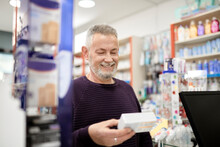 Smiling Customer Holding Box Of Medicine At Pharmacy Store