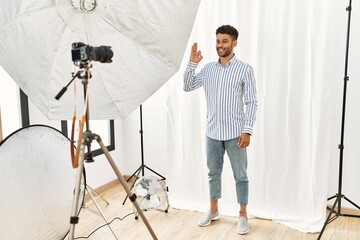 Canvas Print - Arab young man posing as model at photography studio smiling positive doing ok sign with hand and fingers. successful expression.