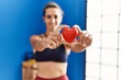 © Krakenimages.com - Young hispanic woman smiling confident holding heart at sport center