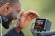 © PheelingsMedia - Videographer with black skin checking camera monitor