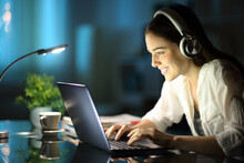 Woman With Headphones Using Laptop In The Night