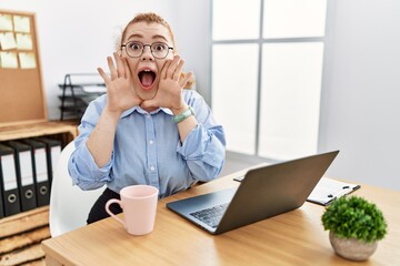 Canvas Print - Young redhead woman working at the office using computer laptop smiling cheerful playing peek a boo with hands showing face. surprised and exited