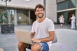 Young hispanic man smiling confident using laptop at street