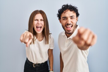 Canvas Print - Young couple wearing casual clothes standing together pointing displeased and frustrated to the camera, angry and furious with you