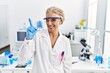 © Krakenimages.com - Middle age blonde woman working at scientist laboratory pointing finger up with successful idea. exited and happy. number one.