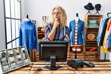 Wall Mural - Middle age blonde woman working as manager at retail boutique looking confident at the camera with smile with crossed arms and hand raised on chin. thinking positive.