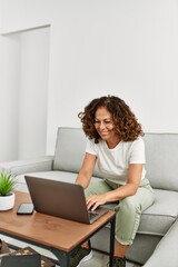 Canvas Print - Middle age hispanic woman smiling confident using laptop at home