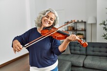 Middle Age Grey-haired Artist Woman Playing Violin Standing At Home.