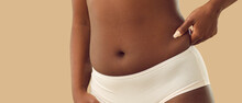 Normalizing Body Flaws, Accepting Yourself And Being Confident In Your Imperfection: Plump Young Black Woman In Underwear, With A Cute Naked Belly Button, Pinching Some Body Fat On Her Side, Close Up