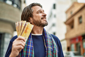 Canvas Print - Middle age handsome man holding norwegian krone banknotes at the town