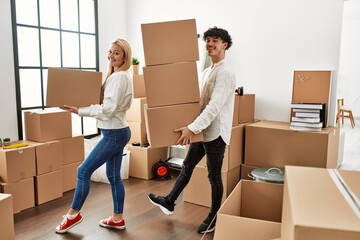 Poster - Young beautiful couple smiling happy holding cardboard boxes at new home.