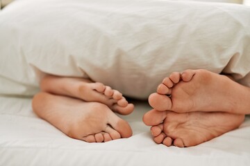 Poster - Couple feet under sheets on the bed at home.