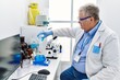 © Krakenimages.com - Middle age grey-haired man wearing scientist uniform pouring liquid on test tube at laboratory
