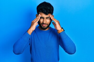 Wall Mural - Arab man with beard wearing casual blue sweater with hand on head for pain in head because stress. suffering migraine.