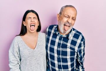 Sticker - Hispanic father and daughter wearing casual clothes sticking tongue out happy with funny expression. emotion concept.